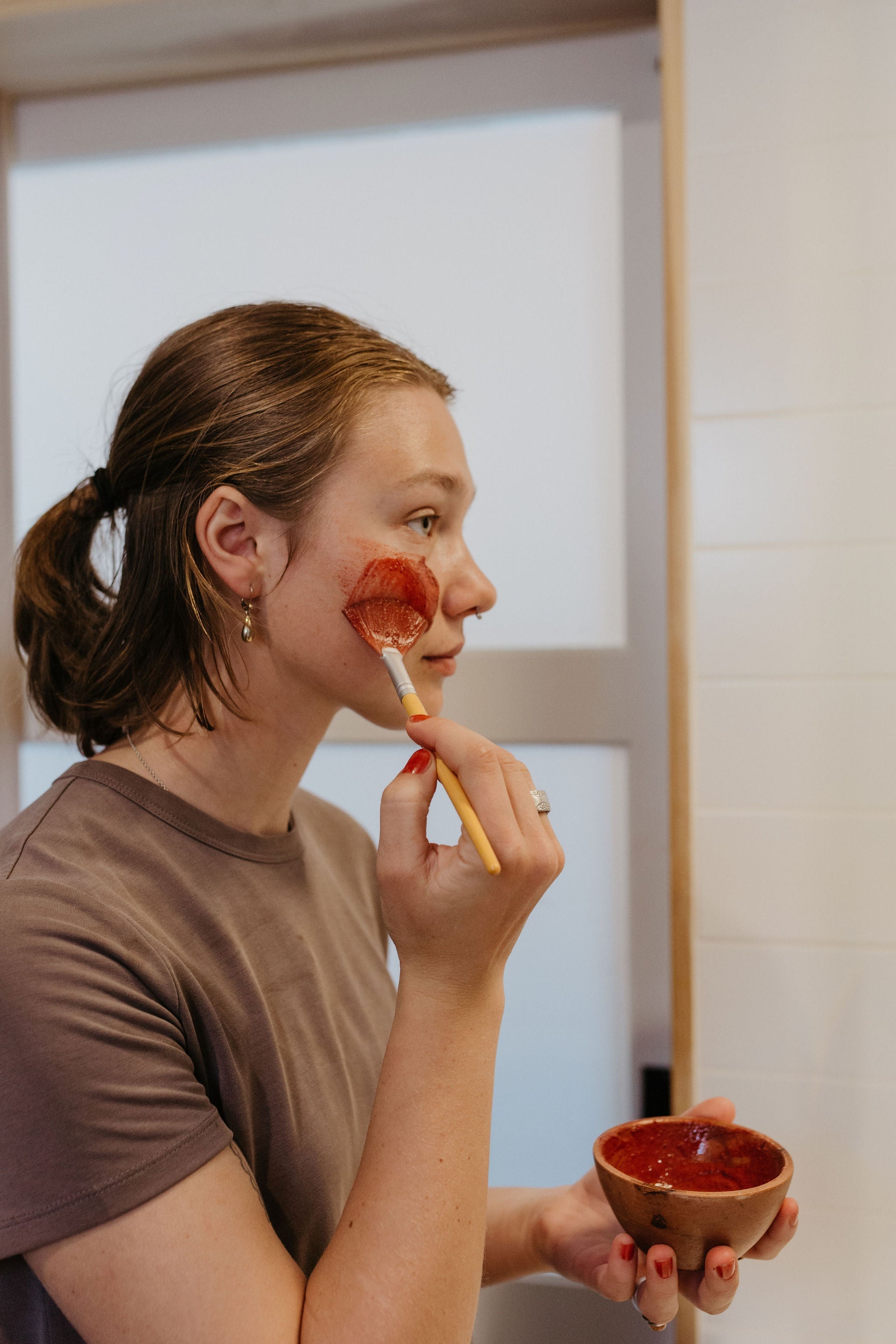 Woman applying flowers & rose clay botanical face mask by Good Flower Farm