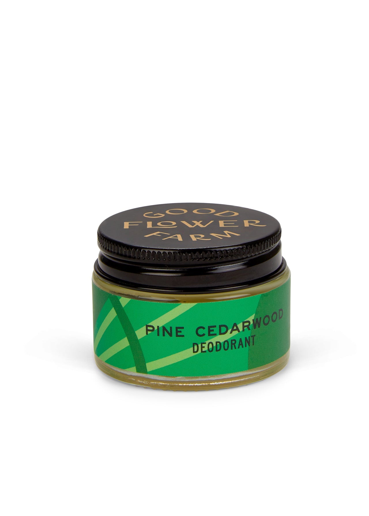 A small jar of Good Flower Farm Pine Cedarwood Deodorant with a bamboo applicator, featuring a green geometric label and black lid. This aluminum-free formula is gentle on sensitive skin. Brand name appears in gold.