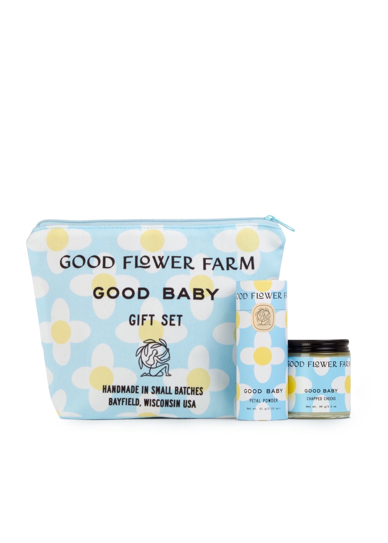 The Good Baby Gift Set by Good Flower Farm includes a blue cosmetic bag with white and yellow floral designs, plus a matching box and jar, featuring baby diaper balm made with gentle botanical ingredients.
