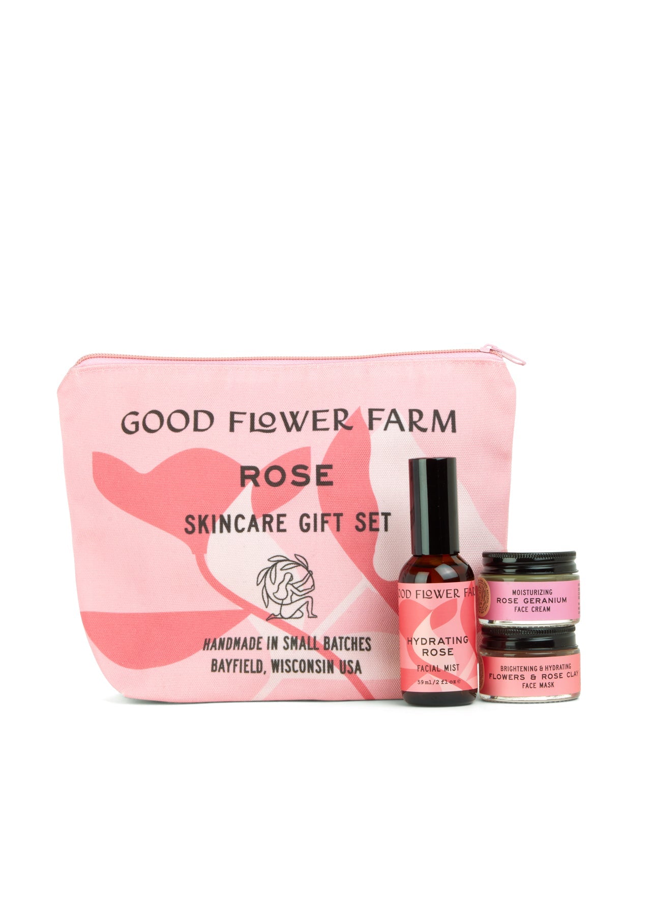 A pink Good Flower Farm Rose Skincare Gift Set cosmetic bag stands behind three floral essentials: Hydrating Rose Facial Mist, Brightening Rose Cream, and Nourishing Face Mask.