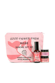 A pink Good Flower Farm Rose Skincare Gift Set cosmetic bag stands behind three floral essentials: Hydrating Rose Facial Mist, Brightening Rose Cream, and Nourishing Face Mask.