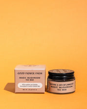 A jar of Good Flower Farm Magic Mushroom Face Mask sits by its box on an orange background. This face mask blends collagen-boosting maitake and shiitake mushrooms with rhassoul clay for soothing, anti-inflammatory care.