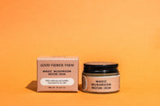A jar and box of Good Flower Farm Magic Mushroom Moisture Cream sit on an orange background. This skincare is made for dry skin, featuring cordyceps oil and adaptogenic maitake, as highlighted on the packaging.
