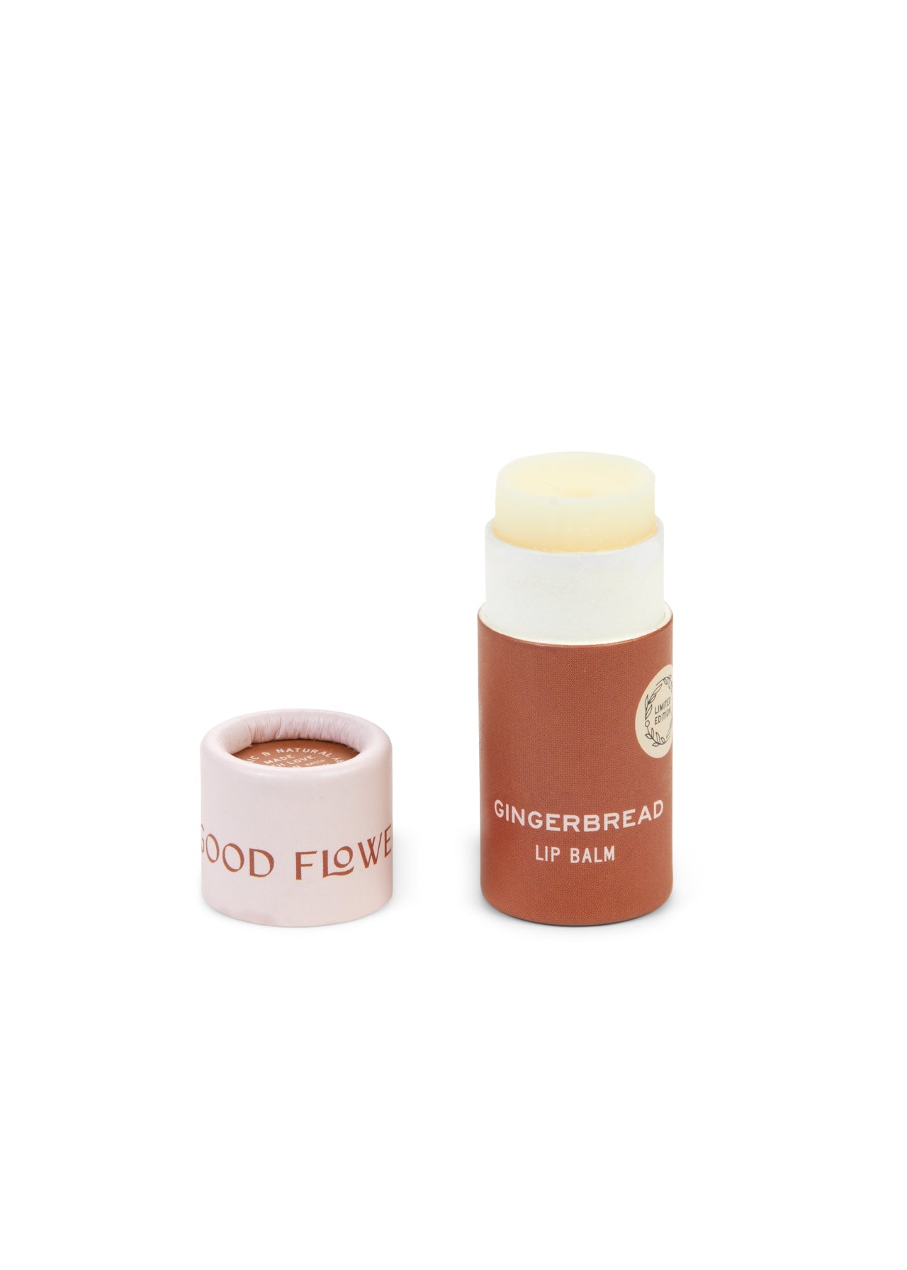 A tube from the SEASONAL LIMITED Holiday Lip Gift Set - NEW by Good Flower Farm with its biodegradable cap showing GOOD FLOWER, brown tube with white text, and light cream coconut oil-infused balm. Cap is removed and placed beside the tube.