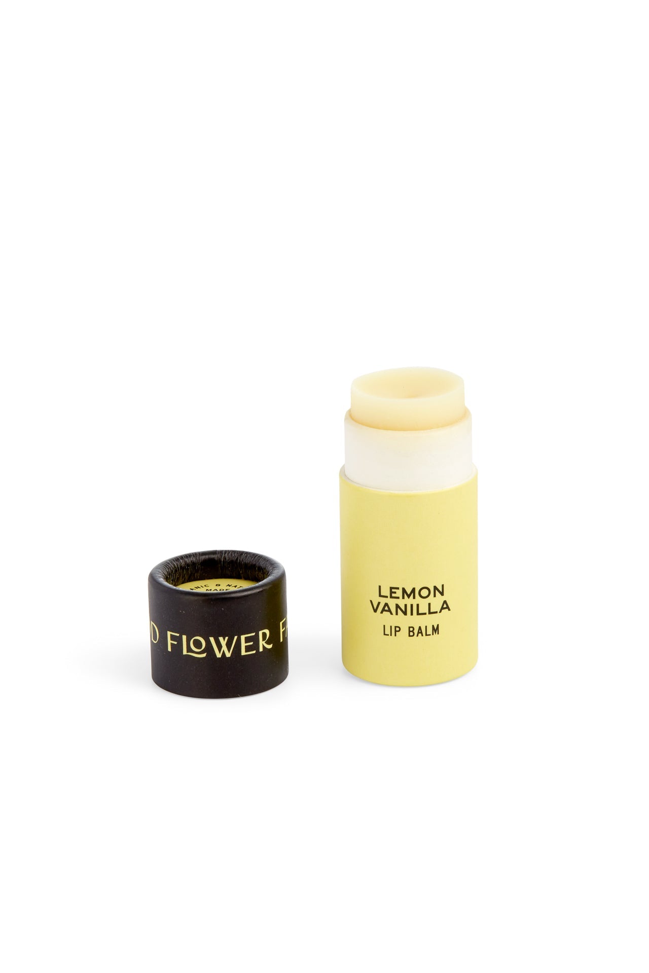A yellow tube of Seconds Lip Balm by Good Flower Farm, labeled LEMON VANILLA LIP BALM, sits with its black cap featuring gold text beside it—showing that Good Flower Farm’s beautiful inside lip care goes beyond looks.